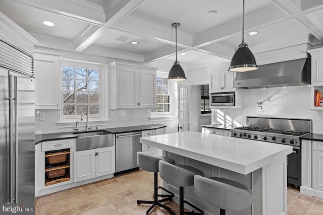 kitchen featuring built in appliances, coffered ceiling, a sink, wall chimney range hood, and beam ceiling