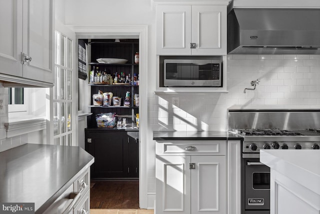 kitchen featuring stainless steel appliances, wall chimney range hood, and white cabinetry