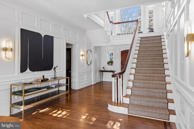 foyer with stairs, a decorative wall, and dark wood-style flooring