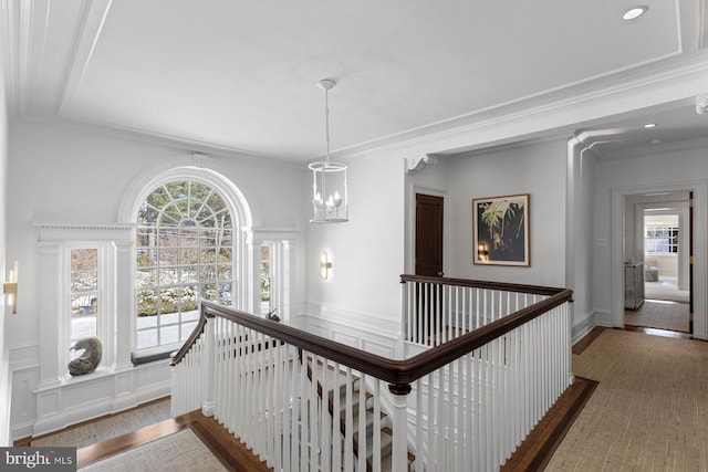 corridor with plenty of natural light, ornamental molding, wood finished floors, and an upstairs landing