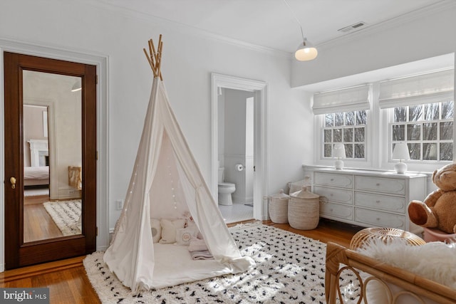 interior space featuring crown molding, visible vents, and wood finished floors