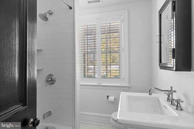 bathroom featuring bathtub / shower combination, toilet, a sink, visible vents, and baseboards