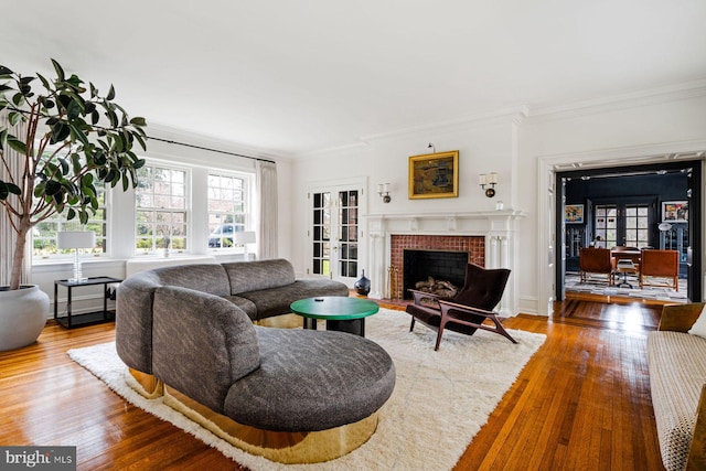 living area featuring hardwood / wood-style flooring, a fireplace, crown molding, and french doors