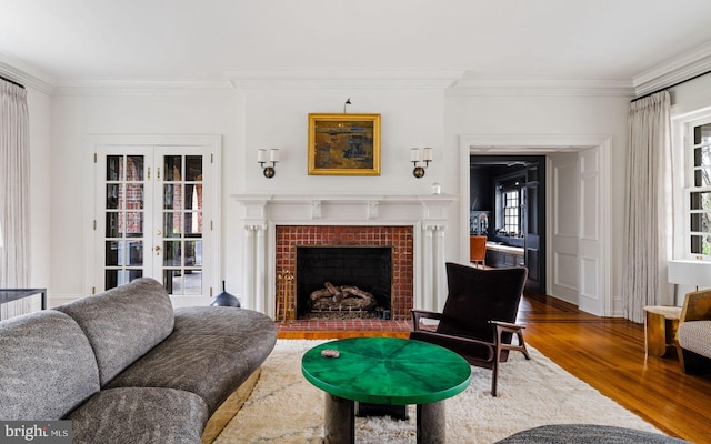 living area featuring a tiled fireplace, ornamental molding, and wood finished floors