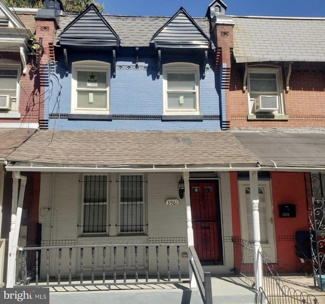 view of property featuring brick siding, a fenced front yard, a shingled roof, and cooling unit