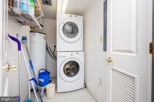 laundry room featuring tile patterned flooring, laundry area, baseboards, and stacked washer / drying machine