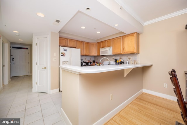 kitchen featuring white appliances, visible vents, baseboards, a peninsula, and tasteful backsplash