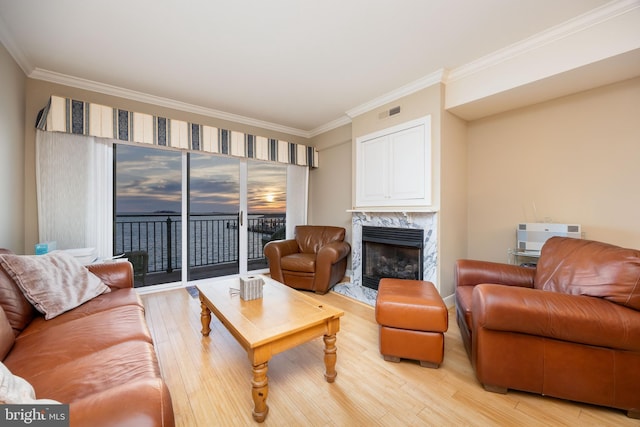 living room with crown molding, a fireplace, light wood-style floors, and visible vents