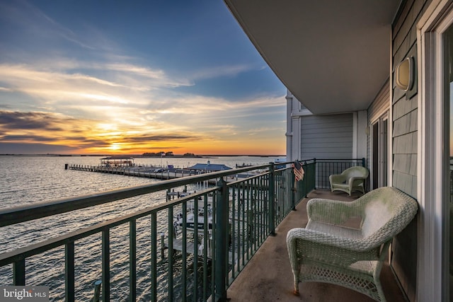 balcony at dusk featuring a water view