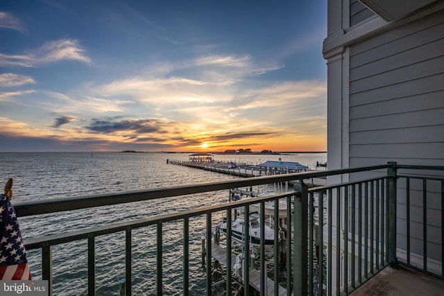 balcony at dusk featuring a water view