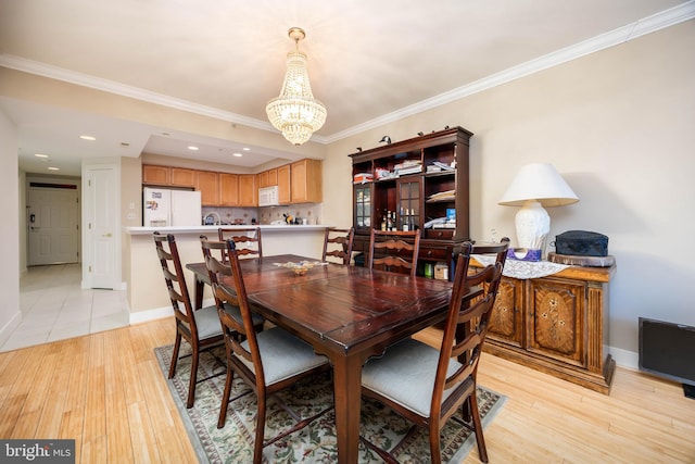 dining space with baseboards, light wood finished floors, an inviting chandelier, recessed lighting, and crown molding