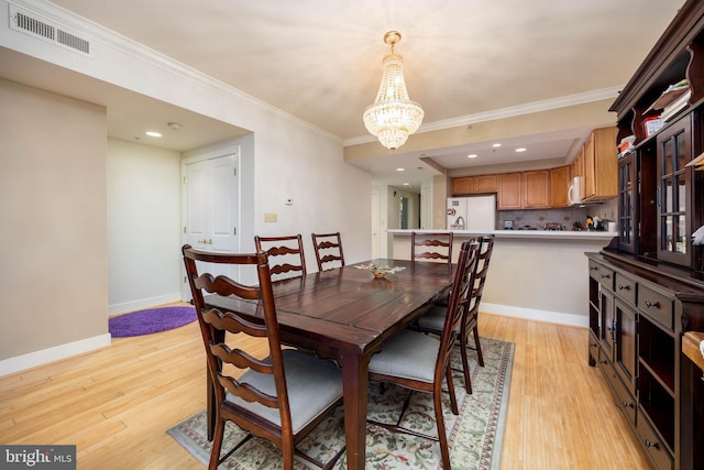 dining space featuring light wood-type flooring, visible vents, ornamental molding, an inviting chandelier, and baseboards