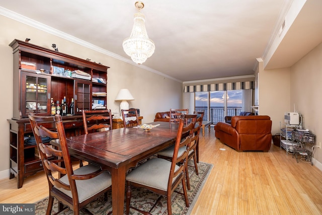 dining space with visible vents, crown molding, baseboards, light wood-type flooring, and an inviting chandelier