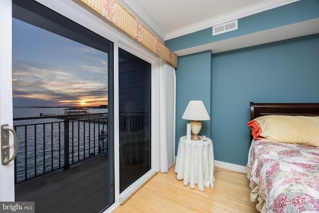 bedroom featuring visible vents, crown molding, baseboards, a water view, and wood finished floors