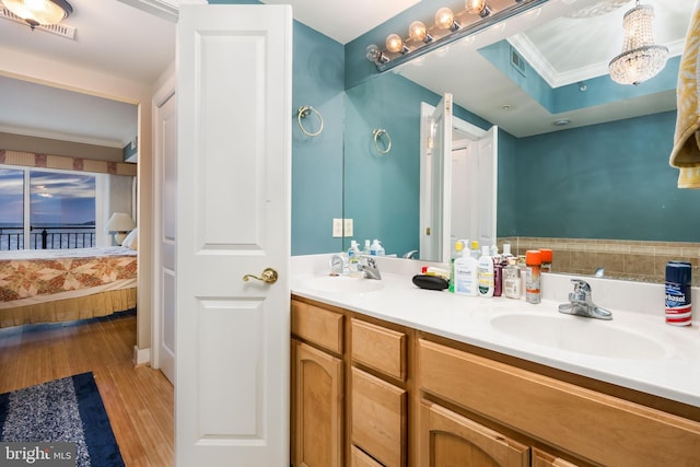 full bathroom featuring a sink, double vanity, wood finished floors, and crown molding