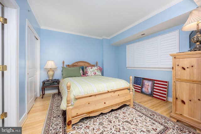 bedroom with light wood-style flooring, baseboards, visible vents, and ornamental molding