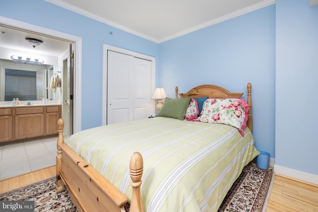 bedroom featuring baseboards, light wood-style flooring, a sink, a closet, and crown molding