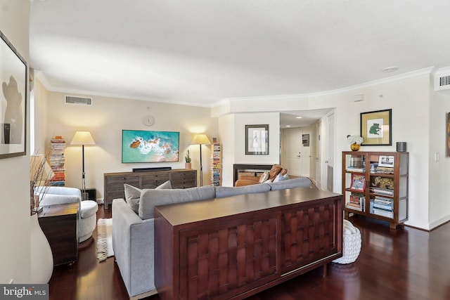 living area featuring dark wood-type flooring, baseboards, visible vents, and ornamental molding