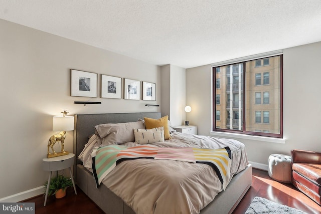 bedroom with wood finished floors, baseboards, and a textured ceiling