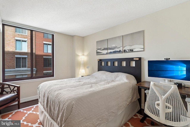 bedroom with a textured ceiling, baseboards, and wood finished floors