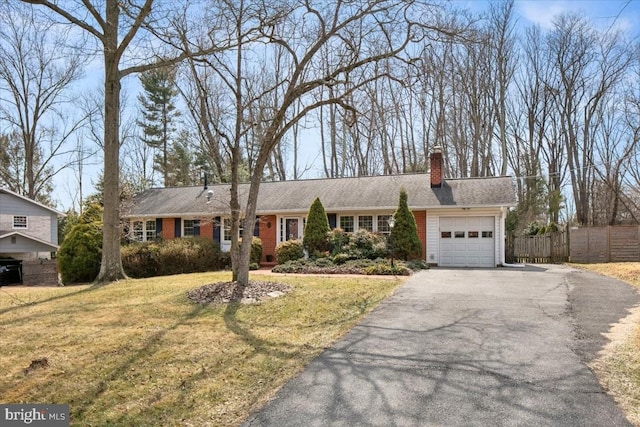 ranch-style home with a garage, brick siding, fence, driveway, and a front lawn