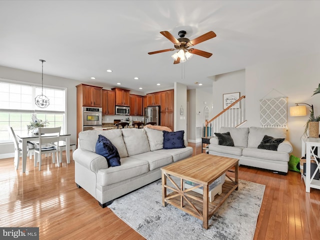 living area featuring light wood finished floors, baseboards, a ceiling fan, stairs, and recessed lighting