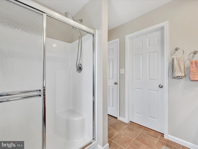 bathroom featuring tile patterned floors, a shower stall, and baseboards