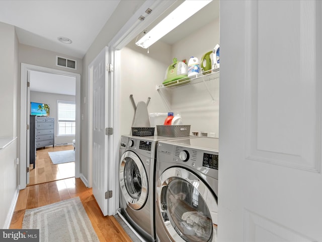 washroom featuring light wood-style flooring, laundry area, visible vents, baseboards, and independent washer and dryer