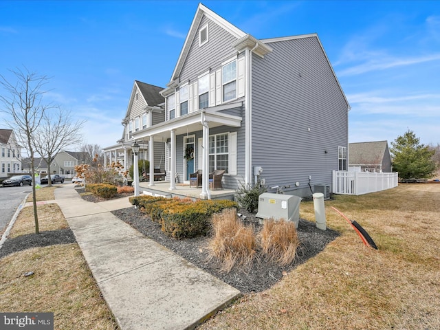 view of property exterior with central air condition unit, a porch, a lawn, fence, and a residential view