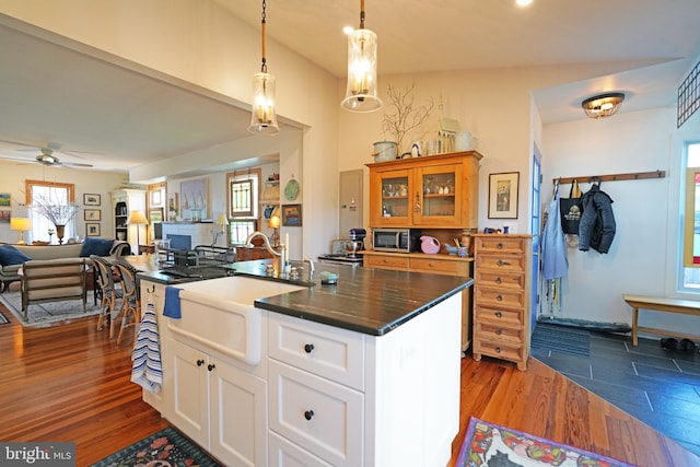 kitchen with stainless steel microwave, dark wood-type flooring, glass insert cabinets, open floor plan, and a sink