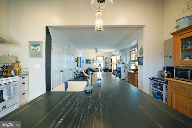 kitchen with gas range gas stove, a sink, open floor plan, stainless steel microwave, and glass insert cabinets