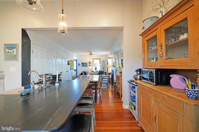 kitchen featuring beverage cooler, glass insert cabinets, stainless steel microwave, dark wood-type flooring, and wooden counters