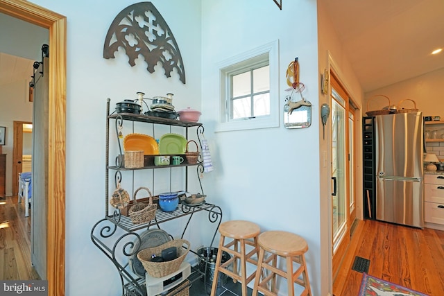 interior space featuring freestanding refrigerator, a barn door, visible vents, and wood finished floors