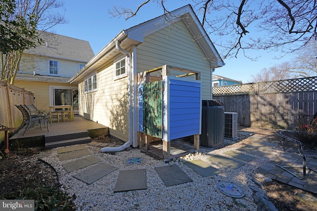 rear view of property with fence, cooling unit, and a wooden deck