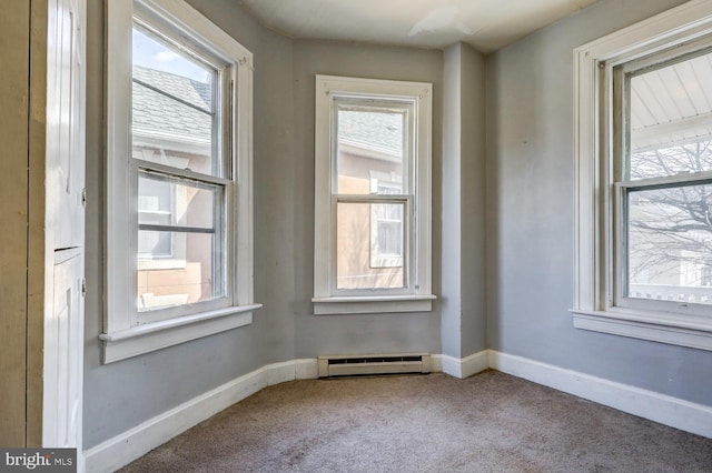 spare room featuring a baseboard heating unit, carpet, and baseboards