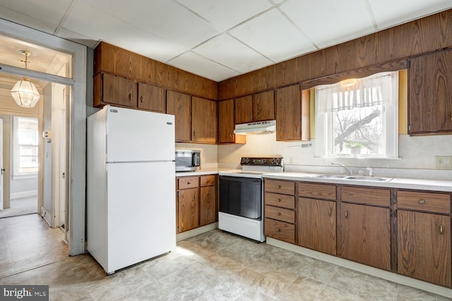 kitchen featuring stainless steel microwave, electric range, freestanding refrigerator, a sink, and under cabinet range hood