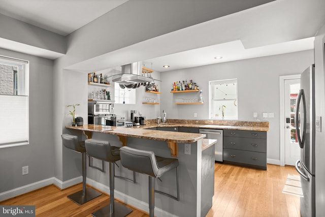 kitchen featuring open shelves, a peninsula, appliances with stainless steel finishes, and a healthy amount of sunlight