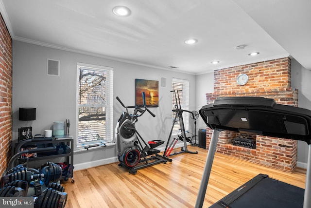 workout area with plenty of natural light, brick wall, crown molding, and hardwood / wood-style flooring