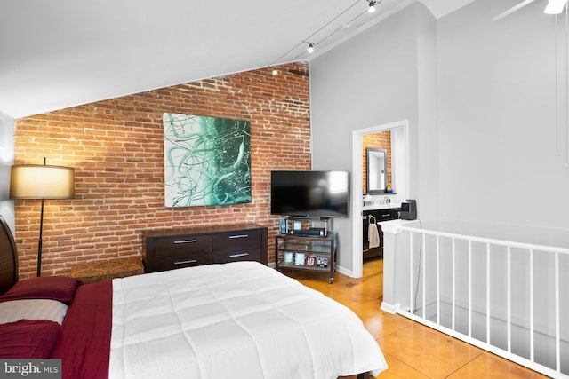 bedroom featuring light tile patterned floors, brick wall, rail lighting, and vaulted ceiling