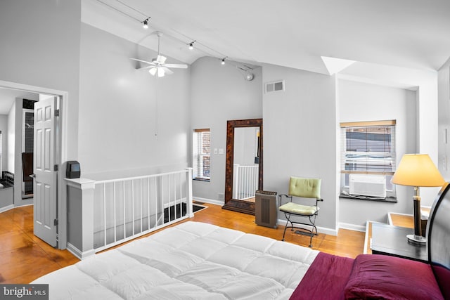 bedroom featuring cooling unit, wood finished floors, visible vents, baseboards, and track lighting