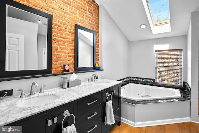 full bath with double vanity, a jetted tub, a skylight, and a sink