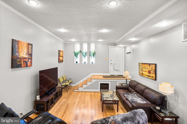 living room featuring stairway, a textured ceiling, crown molding, and wood-type flooring