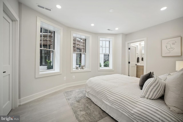 bedroom with baseboards, visible vents, ensuite bath, light wood-style flooring, and recessed lighting