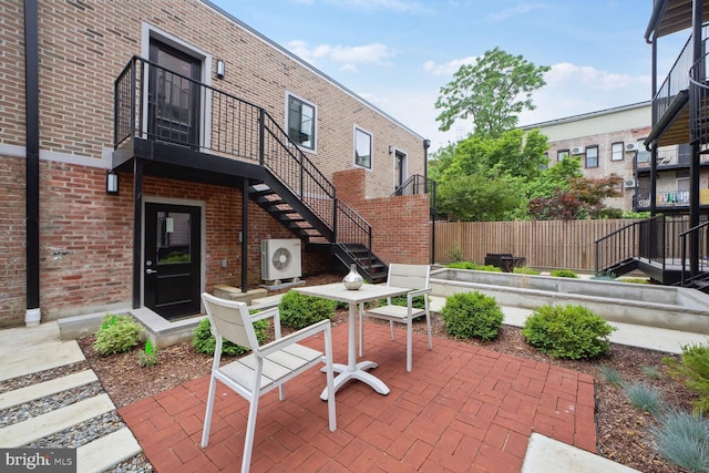 view of patio / terrace featuring stairs, ac unit, outdoor dining area, and fence