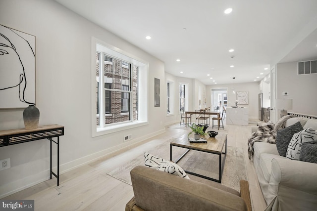 living room with baseboards, recessed lighting, visible vents, and light wood-style floors