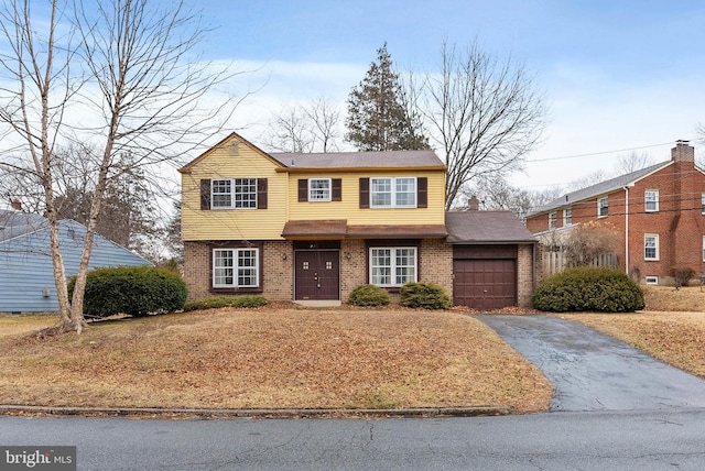 colonial house with aphalt driveway, brick siding, and a garage