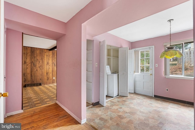 interior space featuring light wood-style flooring, wooden walls, visible vents, baseboards, and washer / clothes dryer