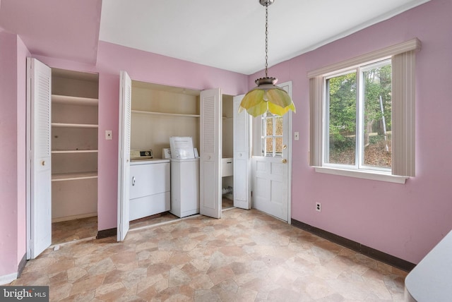 washroom featuring laundry area, stone finish flooring, baseboards, and washing machine and clothes dryer