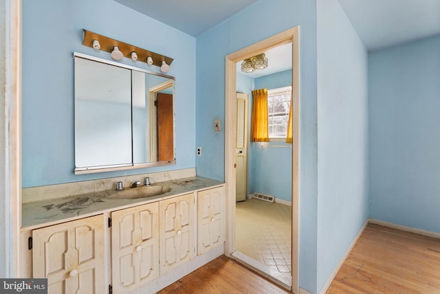 bathroom with baseboards, wood finished floors, and vanity