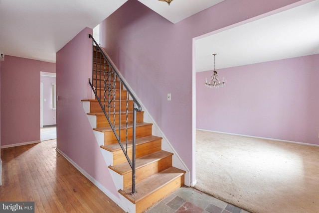 staircase with a chandelier, baseboards, and wood finished floors